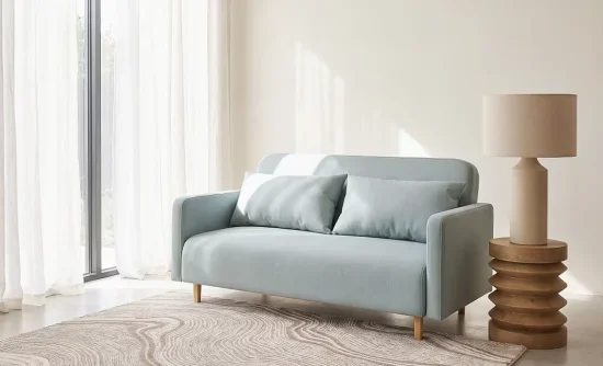 Canapé vert d'eau aux coussins bleu pâle dans un salon lumineux aux voilages blancs