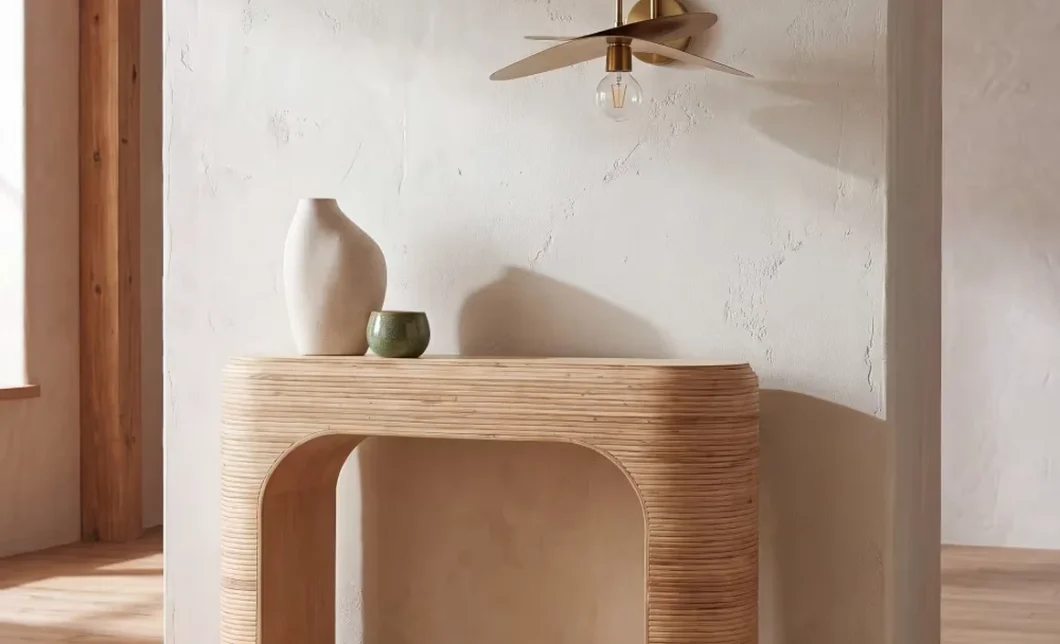 Applique murale zen en laiton et bois au-dessus d'une console arrondie dans une entrée aux murs beiges