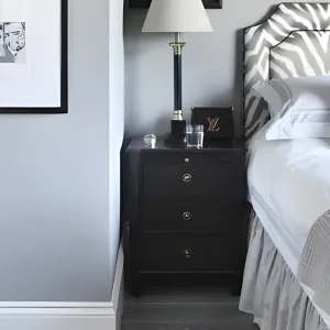 Chambre en blanc et gris avec tête de lit zébrée, table de chevet noire et cadres en noir et blanc