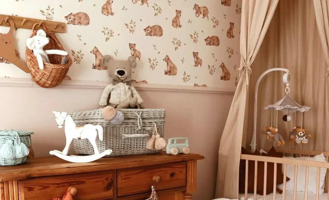 Chambre de bébé avec papier peint à motif ours, commode en bois ancienne, peluche ourson et cheval à bascule