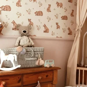 Chambre de bébé avec papier peint à motif ours, commode en bois ancienne, peluche ourson et cheval à bascule