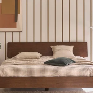 Chambre scandinave vintage avec lit en noyer, mur rayé beige, tableau abstrait et tapis blanc moelleux