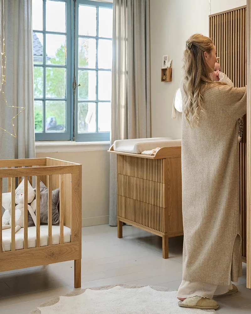 Chambre de bébé zen avec lit en bois naturel, commode à langer cannelée et armoire en bois à lattes
