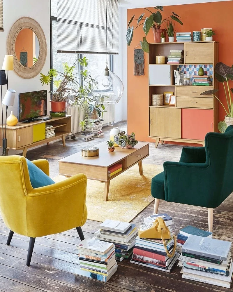 Salon scandinave vintage avec fauteuils jaune et vert, table basse en bois et meubles rétro orange