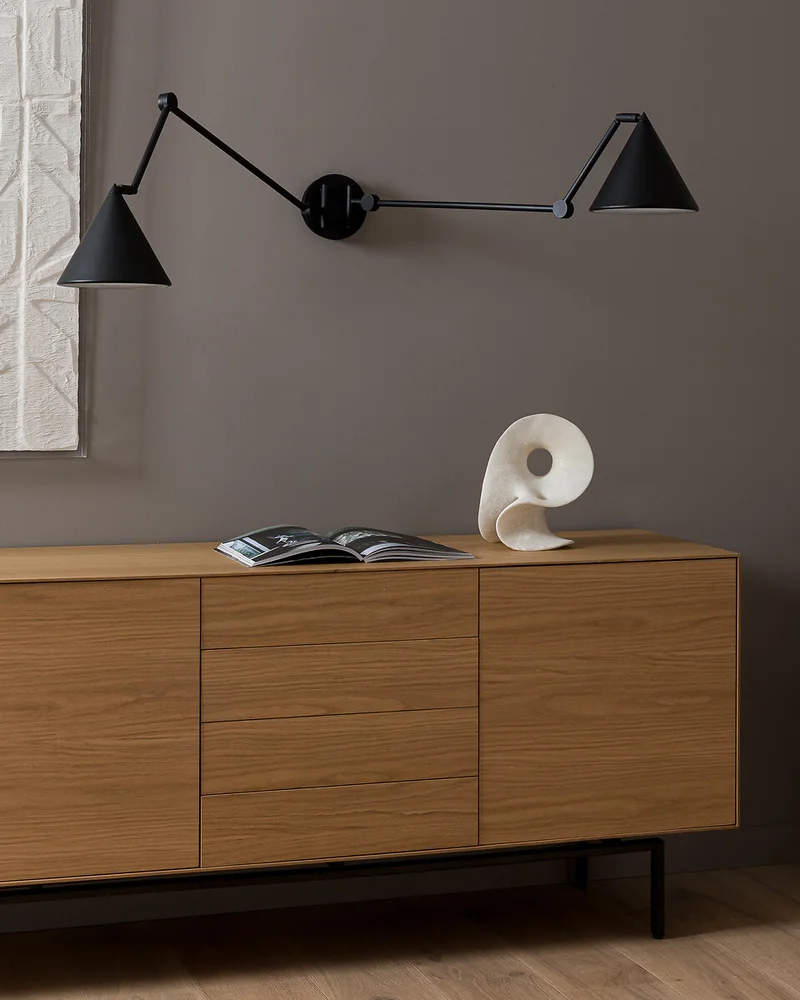Applique murale double bras articulés en métal noir au-dessus d'un buffet en bois clair