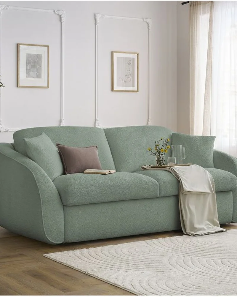 Canapé droit convertible en tissu bouclette vert d'eau aux formes arrondies dans un salon clair