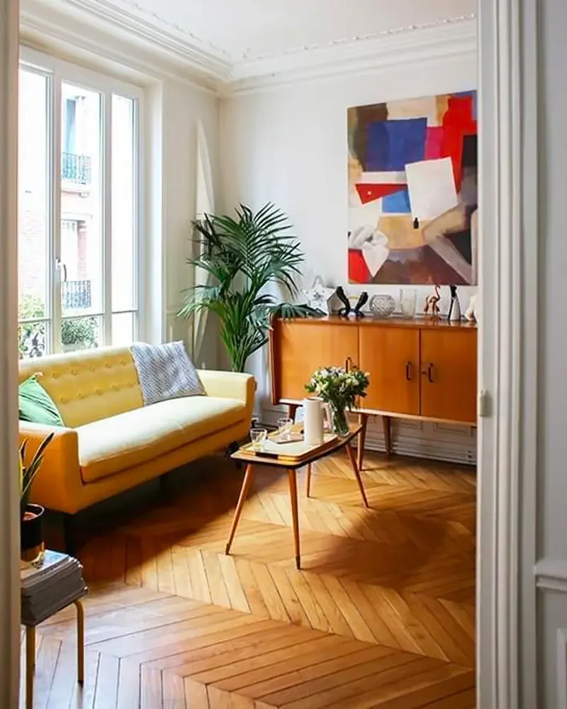 Salon rétro scandinave avec canapé jaune moutarde, enfilade en teck et parquet en point de Hongrie