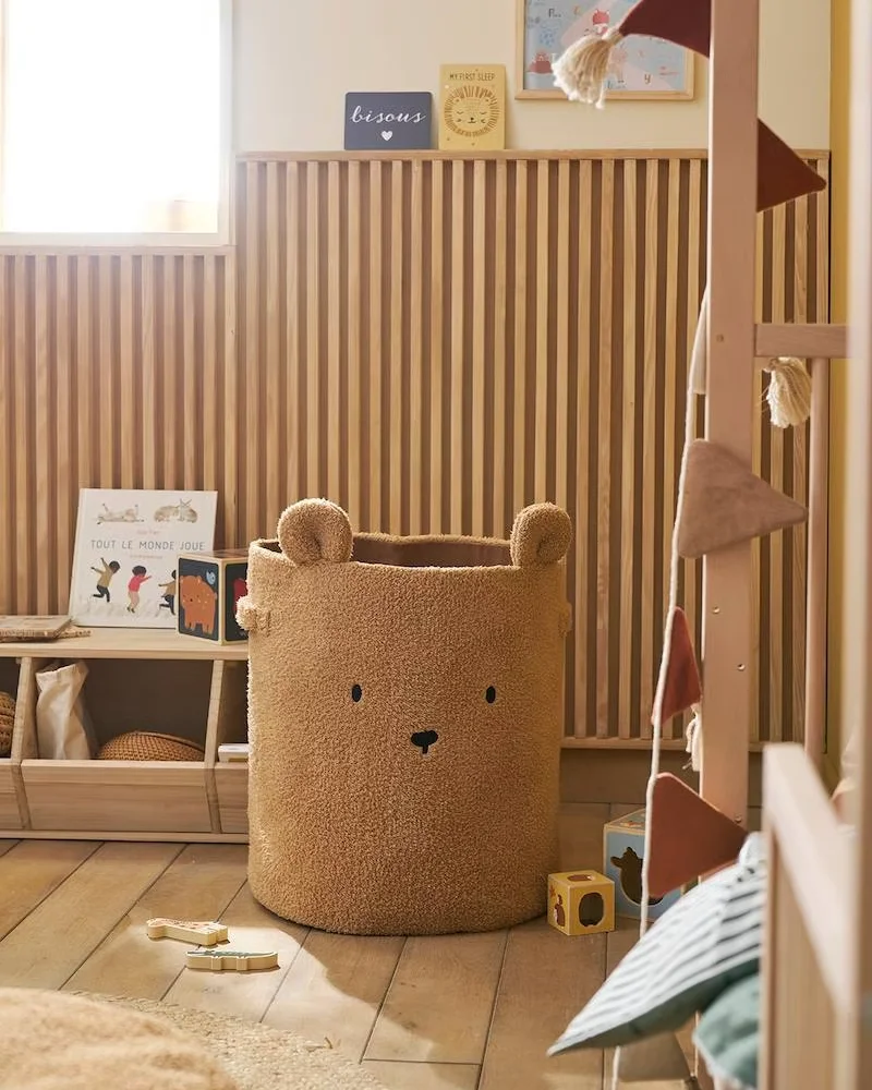 Coin jeu de chambre de bébé avec panier de rangement en forme d'ours, lambris en bois et étagère basse