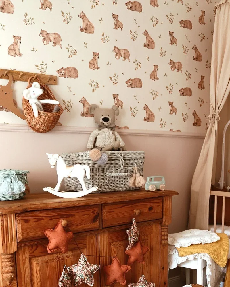 Chambre de bébé avec papier peint ours, soubassement rose poudré, lit à baldaquin et peluche ourson