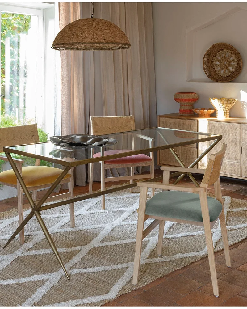 Salle à manger chic avec table en verre et piétement en métal doré, chaises en bois cannées