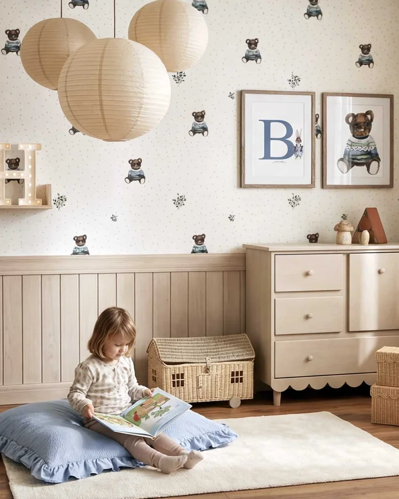 Chambre d'enfant avec papier peint petits ours bleus, commode crème, lampions en papier et lambris