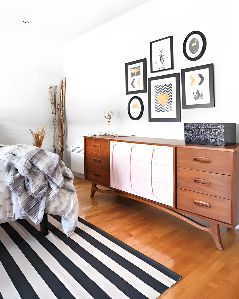 Chambre scandinave vintage avec commode rétro en bois, tapis rayé noir et blanc et cadres graphiques