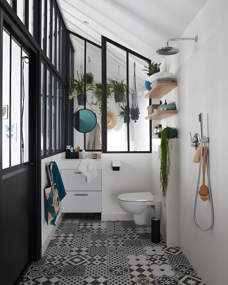 Salle de bain attenante à la chambre séparée par une verrière noire avec carreaux de ciment et plantes