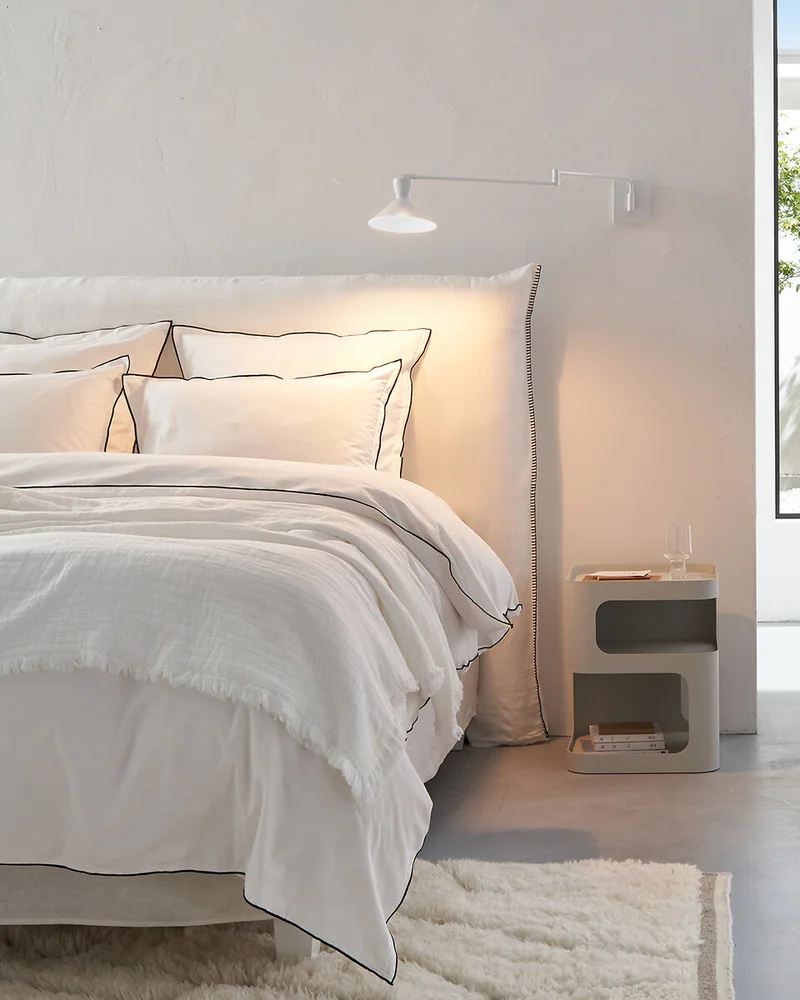 Applique murale zen blanche à bras pivotant au-dessus d'une tête de lit dans une chambre claire