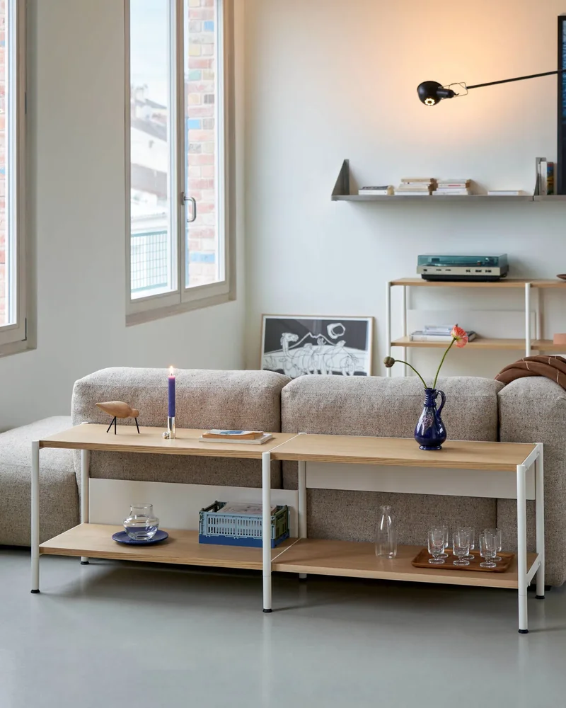 Console basse en métal blanc crème et plateaux en chêne naturel devant un canapé gris