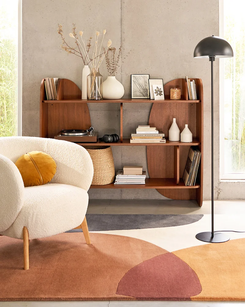 Bibliothèque basse plaqué noyer aux courbes organiques garnie de vases et de livres dans un salon